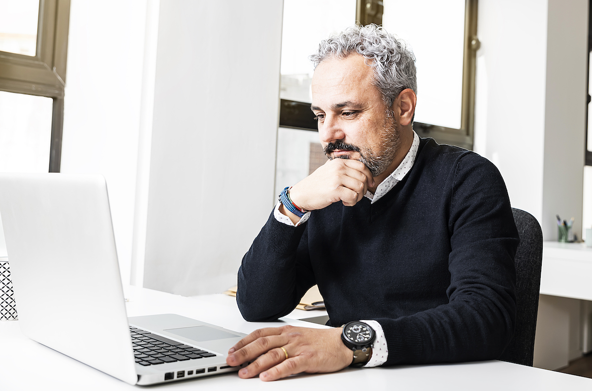 man with gray hair and beard sitting in front of laptop in office - west chicago it consultant